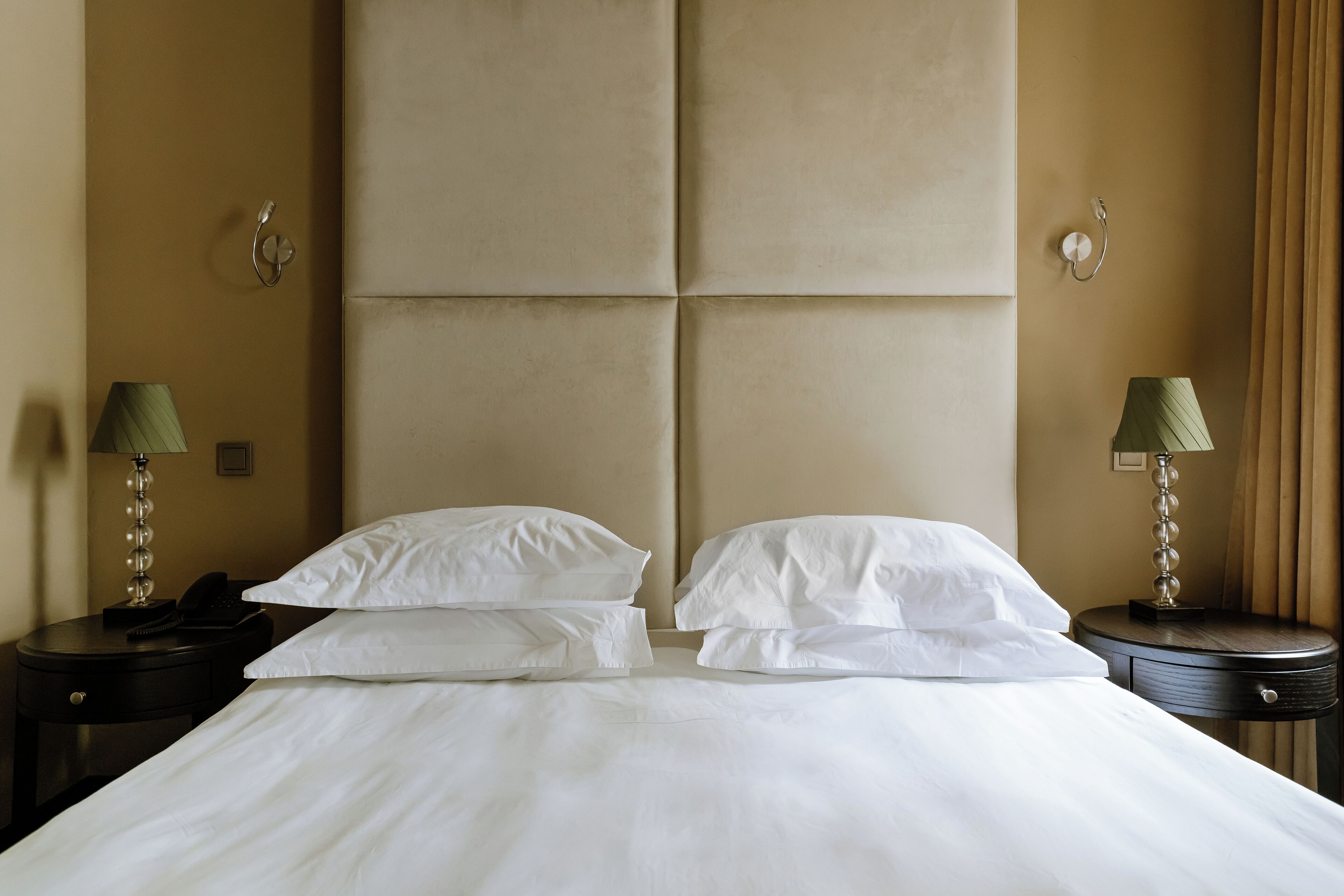 Una habitación de hotel con una cama grande, dos mesitas de noche, un teléfono y lámparas.
