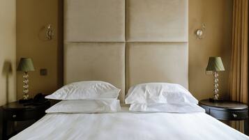 Una habitación de hotel con una cama grande, dos mesitas de noche, un teléfono y lámparas.