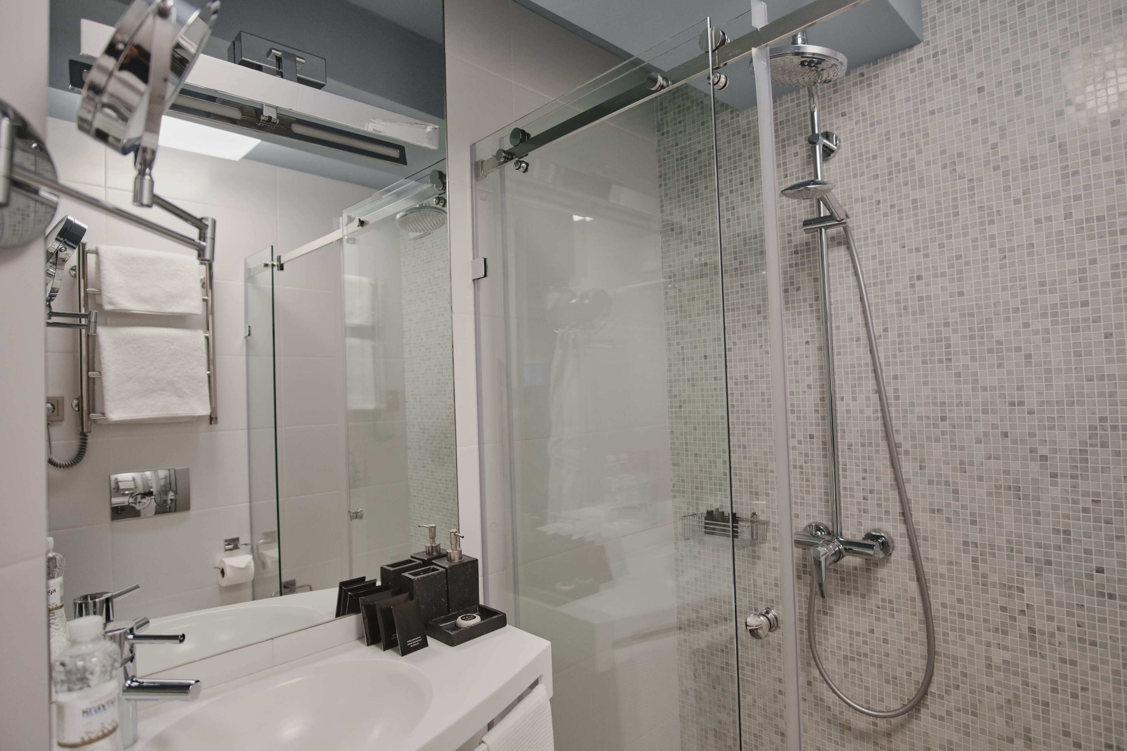 Un baño moderno con ducha de vidrio, lavamanos blanco y espejo.