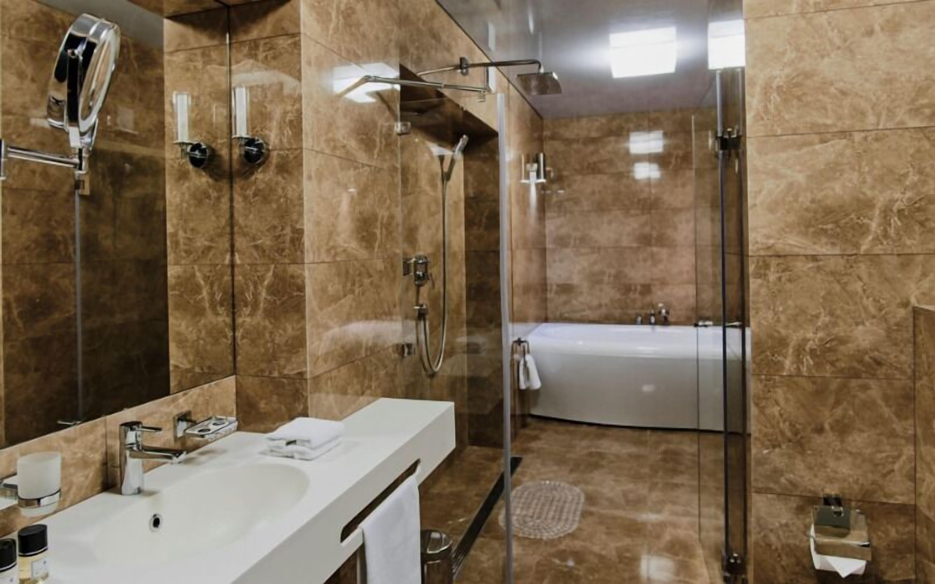 Un baño moderno con lavamanos blanco, cabina de ducha con mampara de vidrio y bañera.