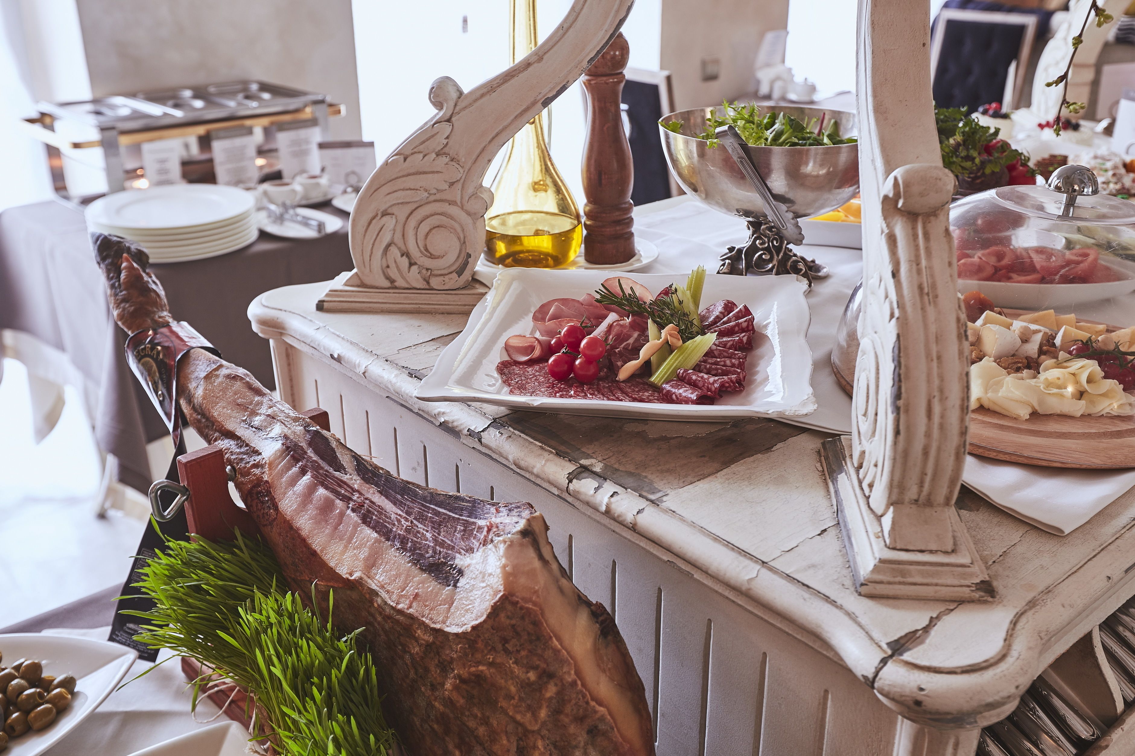 Una mesa de buffet con diversos alimentos, como carnes, quesos y verduras.