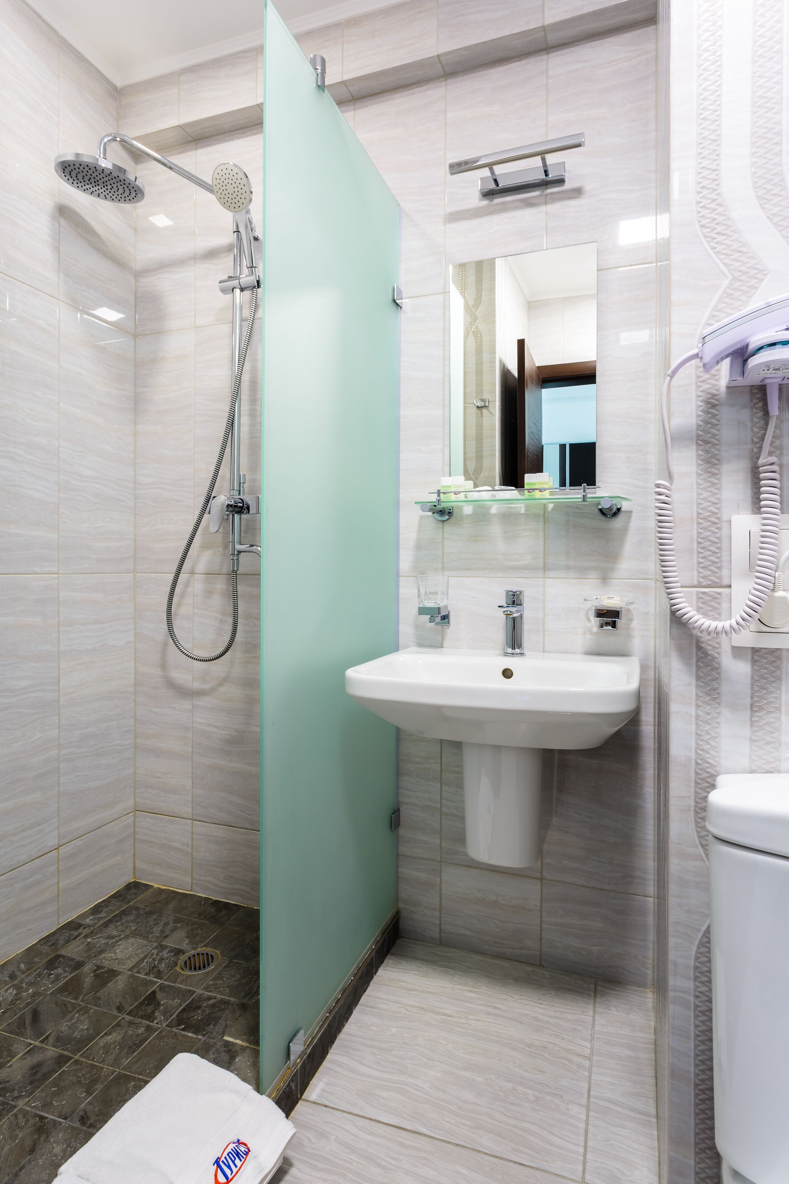 A modern bathroom with a shower, sink, and toilet.