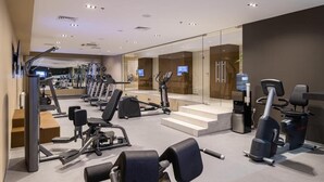 A modern gym with various exercise equipment, a water dispenser, and a TV screen. - Premier Hotel Dnister (Lviv)