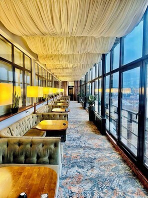 A hotel lobby with a row of plush seating, large windows, and a patterned carpet. - Premier Hotel Dnister (Lviv)
