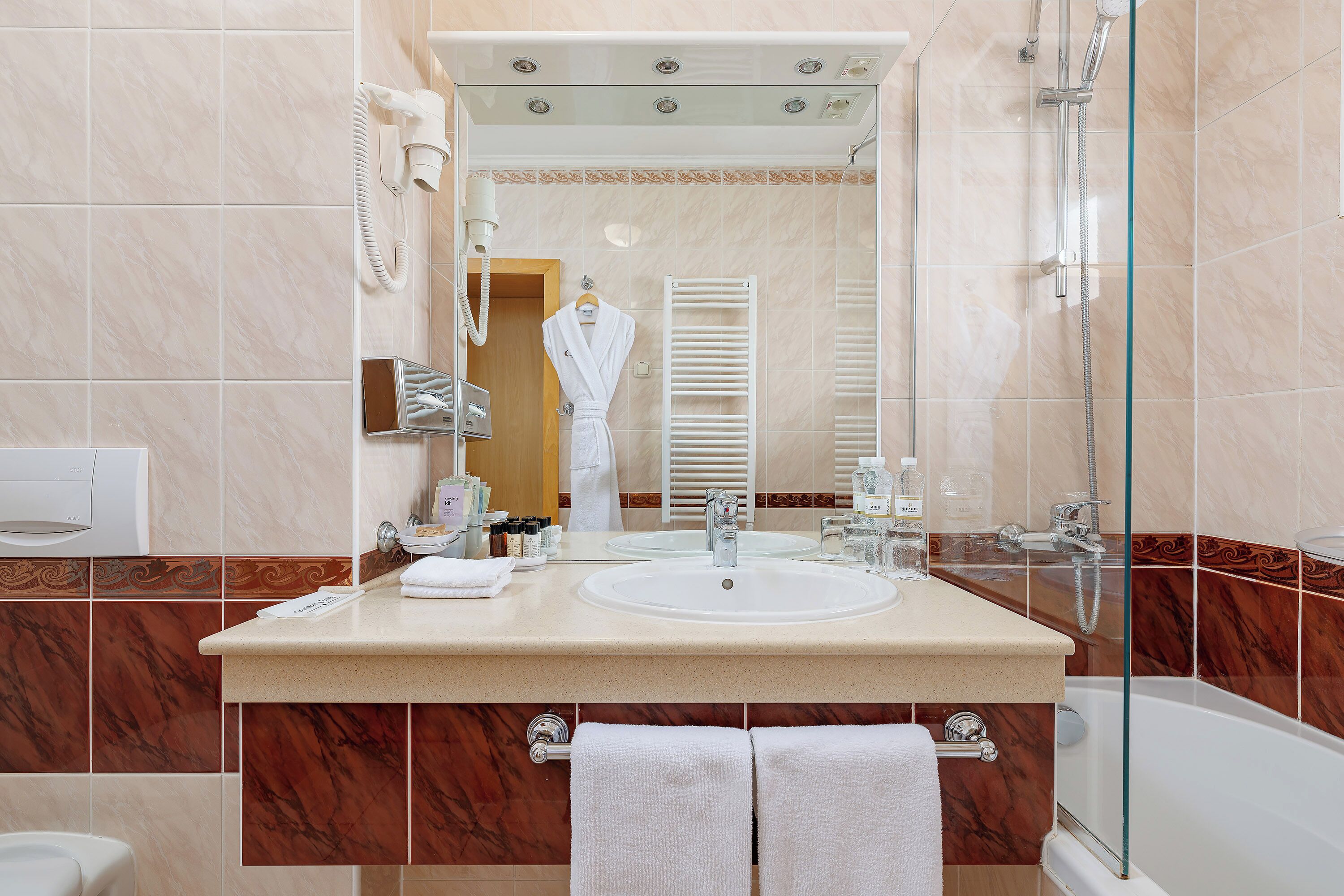 Un baño con un espejo grande, un lavabo, una ducha y un perchero para toallas.