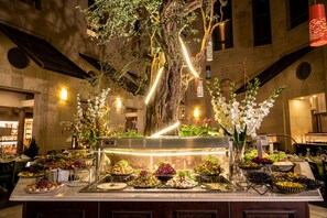 A buffet with various food items and a large tree centerpiece. - Olive Tree Hotel (Jerusalem)