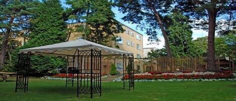 A gazebo in a park with a building in the background.