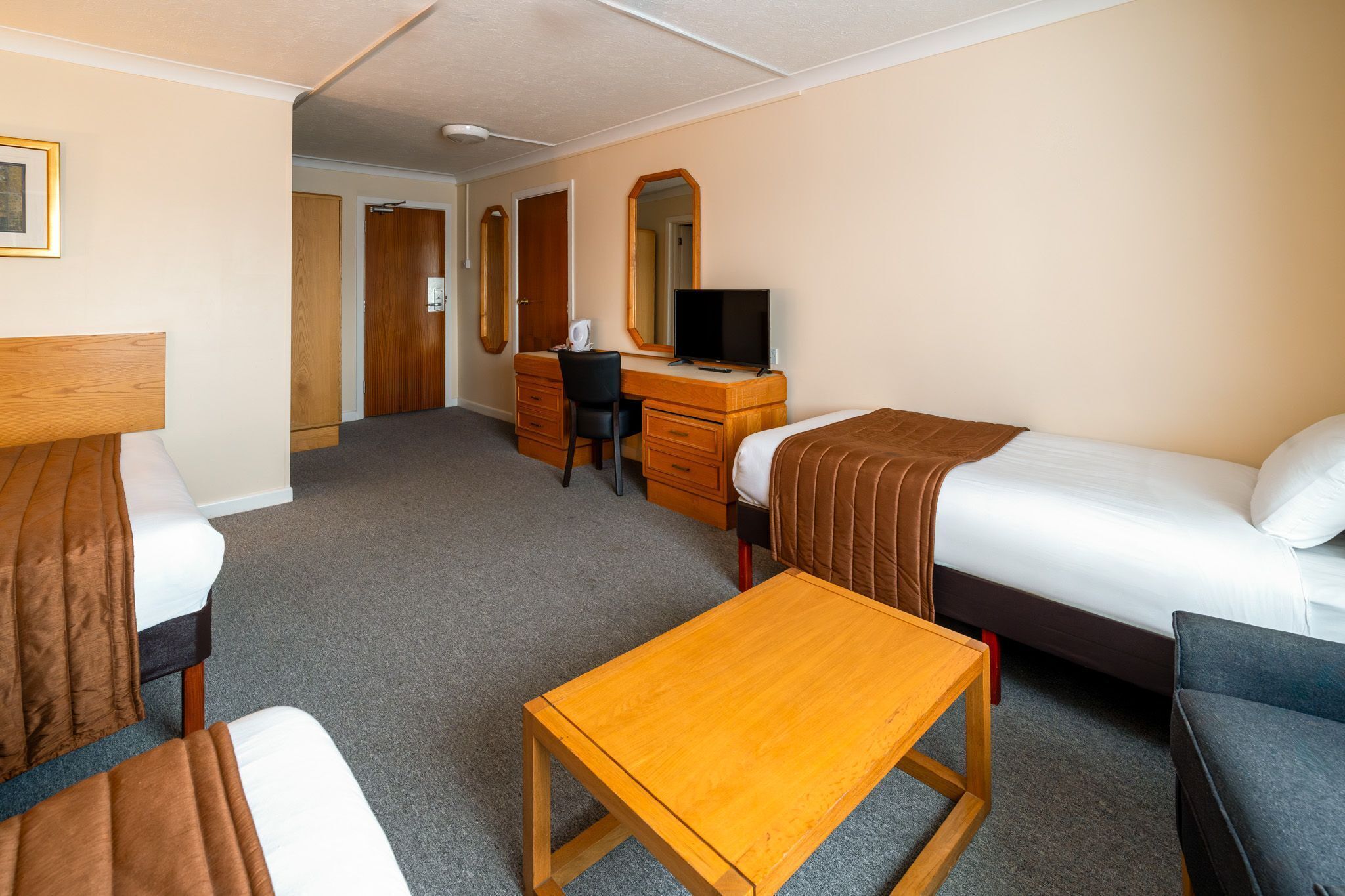 Una habitación de hotel con cama, escritorio, silla, televisor y cómoda.