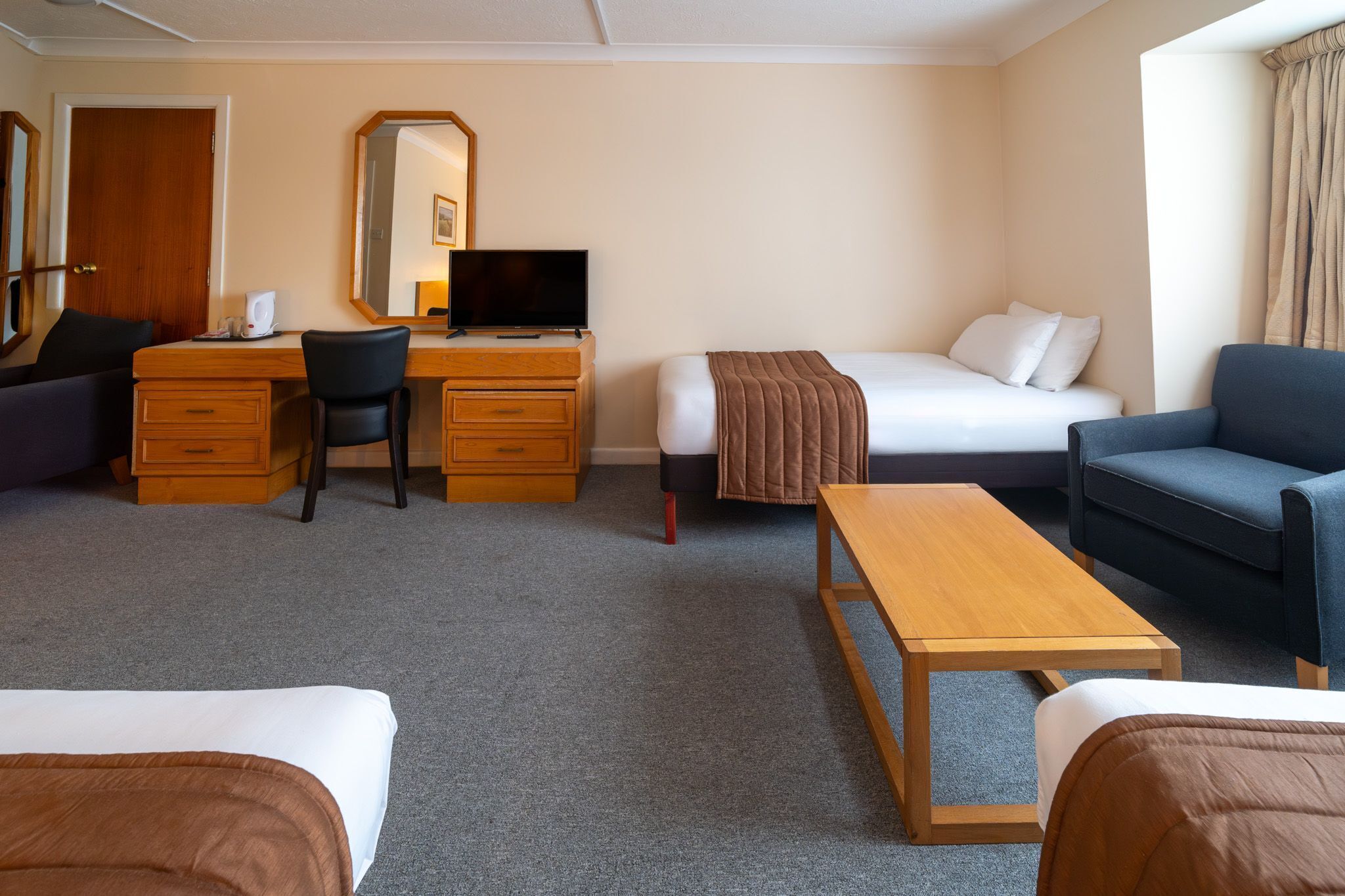 Una habitación de hotel con cama, escritorio con ordenador, silla, sofá y mesa de centro.