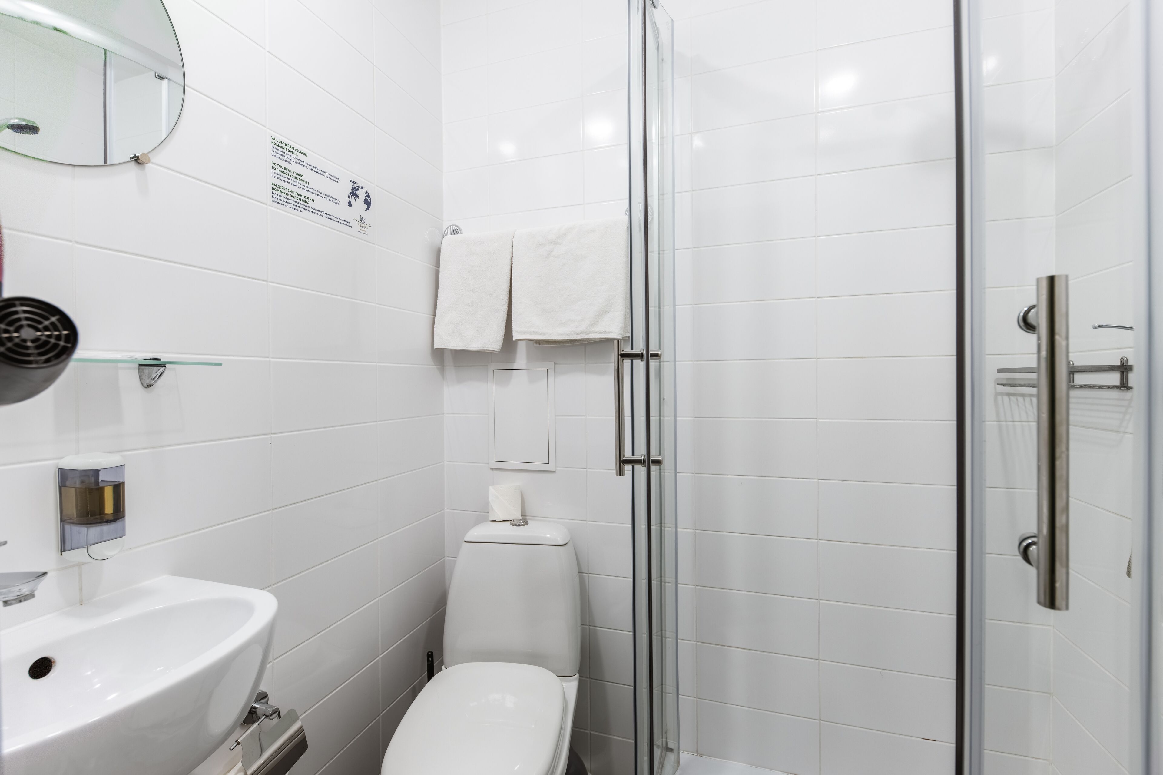 Un baño moderno con cabina de ducha de vidrio, un lavabo blanco y un inodoro.