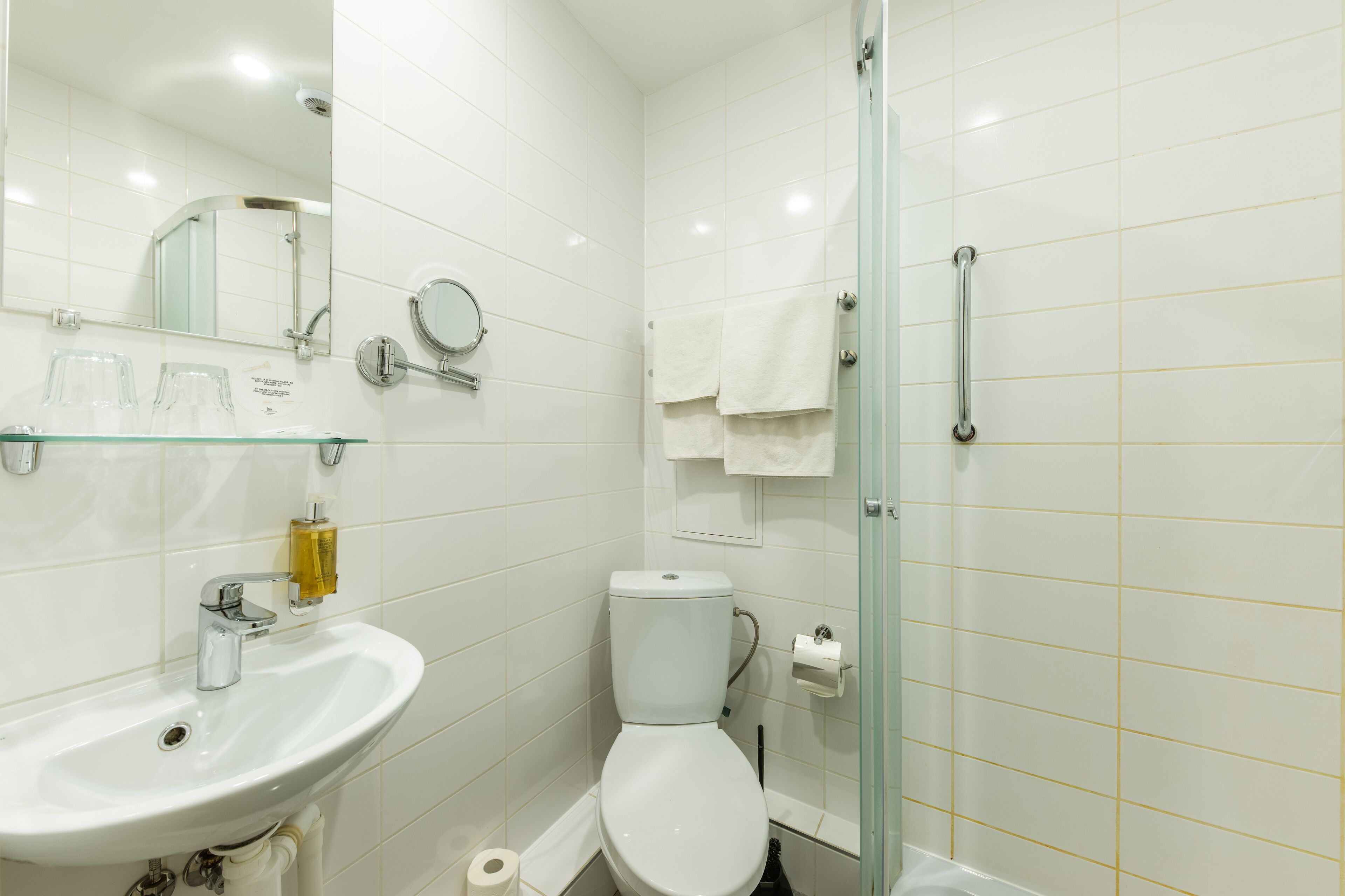 Ein modernes Badezimmer mit Duschkabine aus Glas, einem weißen Waschbecken und einer Toilette.