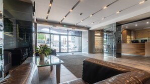 A modern lobby with leather sofas, a glass coffee table, and a reception desk. - Liva Hotel (Liepaja)