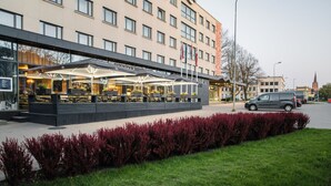 A hotel with outdoor seating, a garden, and a parking area. - Liva Hotel (Liepaja)