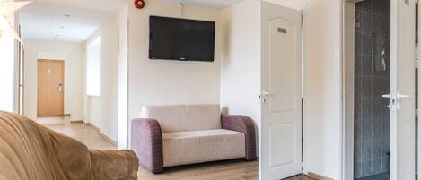 Un moderno salón con un sofá color beige, un sillón púrpura y un televisor de pantalla plana montado en la pared.