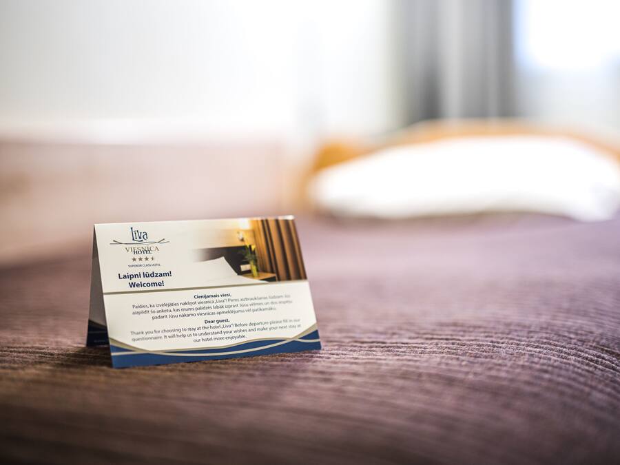 A hotel welcome card on a bed with a blurred background.