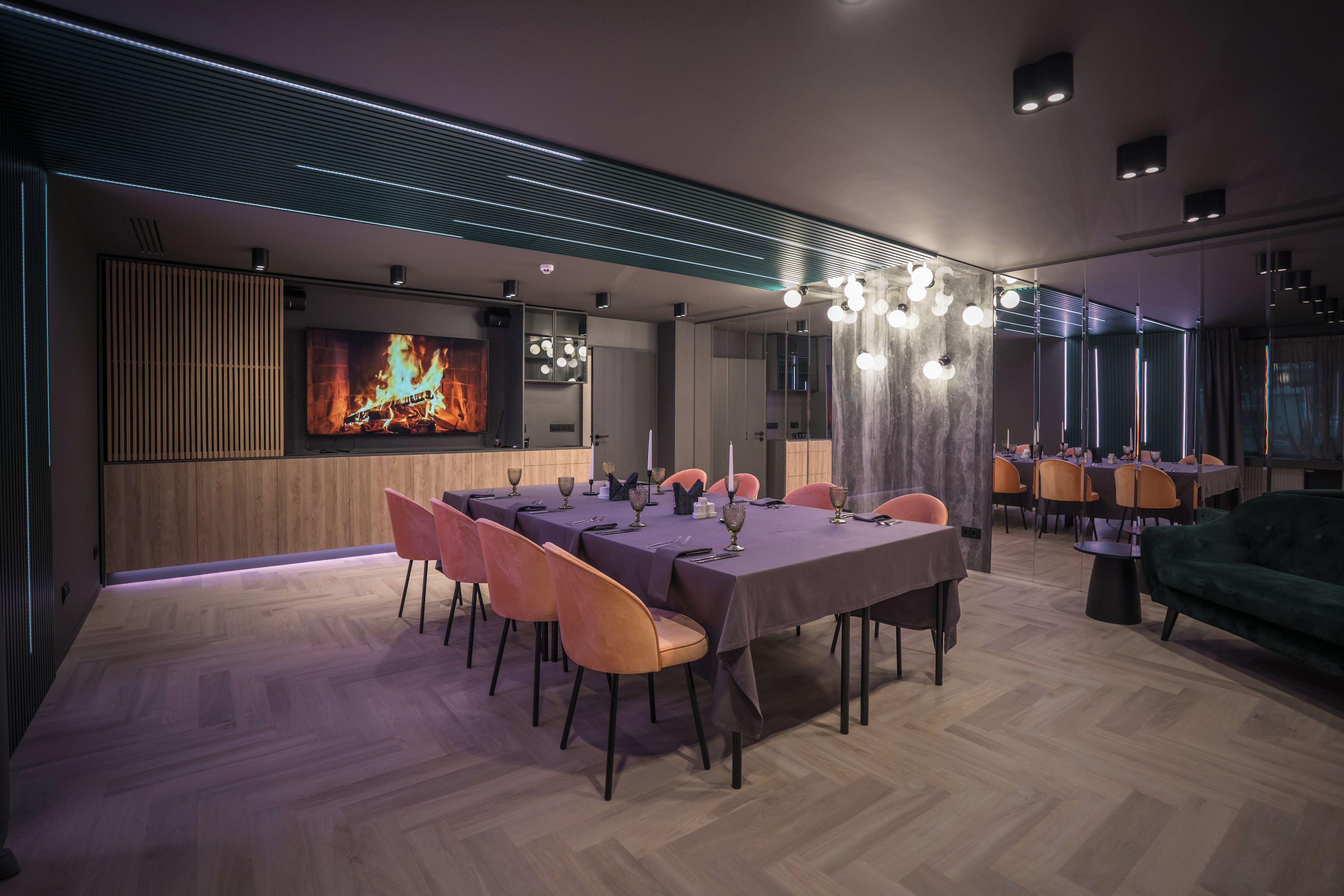 A modern dining area with a long table set for a meal, surrounded by chairs.
