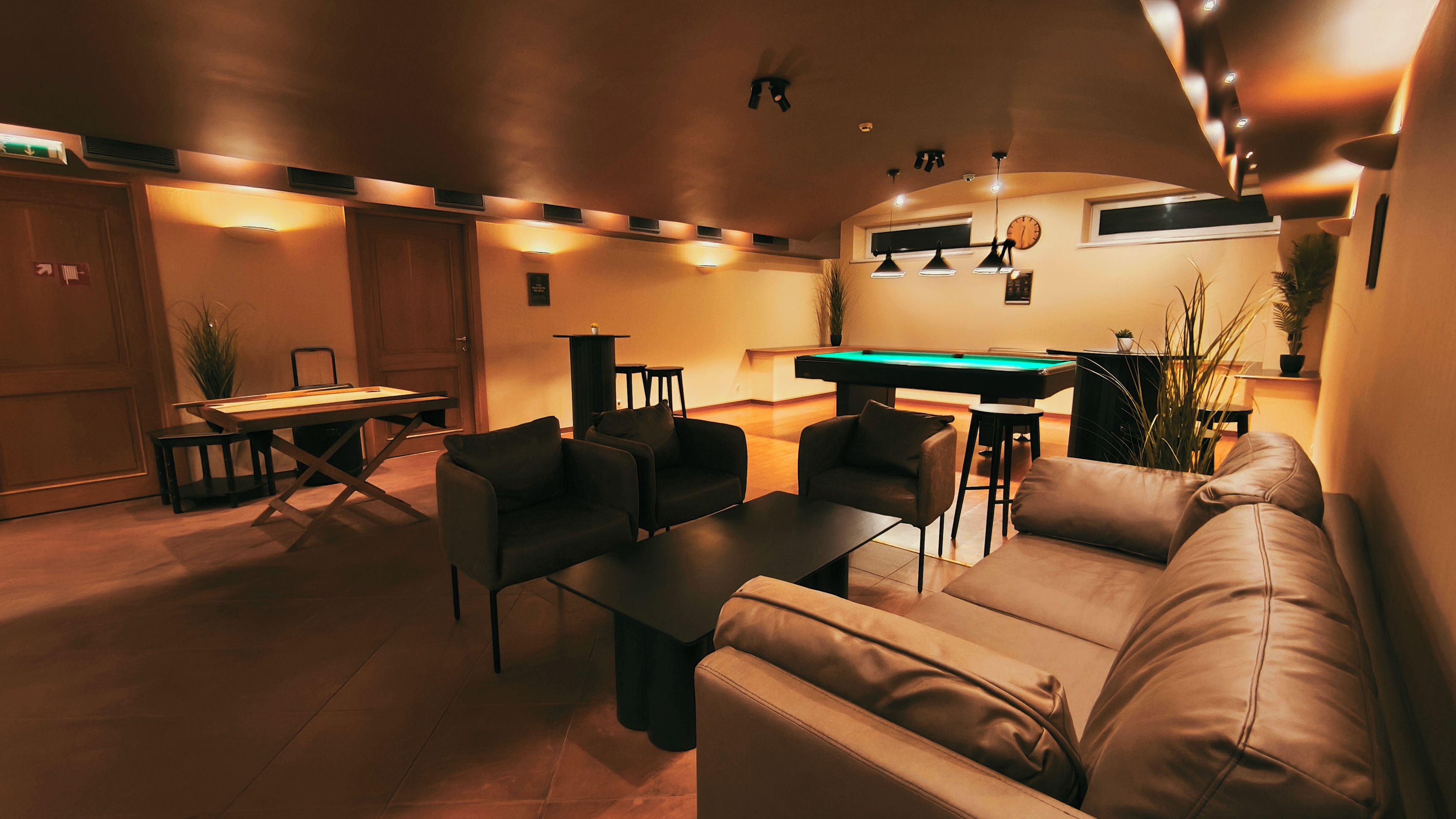 Ein modernes Wohnzimmer mit Billardtisch, Ledersofas und Poolbillard.