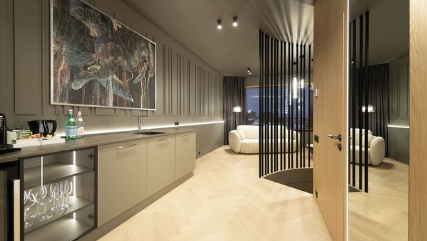 A modern kitchen with a large island, a dining area with a white sofa, and a large abstract painting on the wall. - Amrita Hotel (Liepaja)