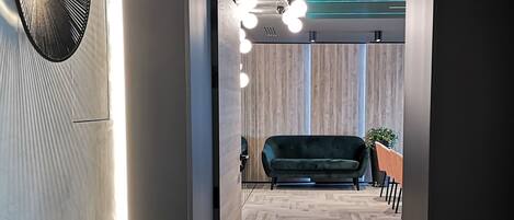 Un interior moderno con suelo de espiga, un sofá verde oscuro y un ventilador de pared.