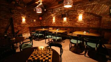 Um restaurante acolhedor com paredes de tijolo, mesas de madeira e cadeiras estofadas verdes.