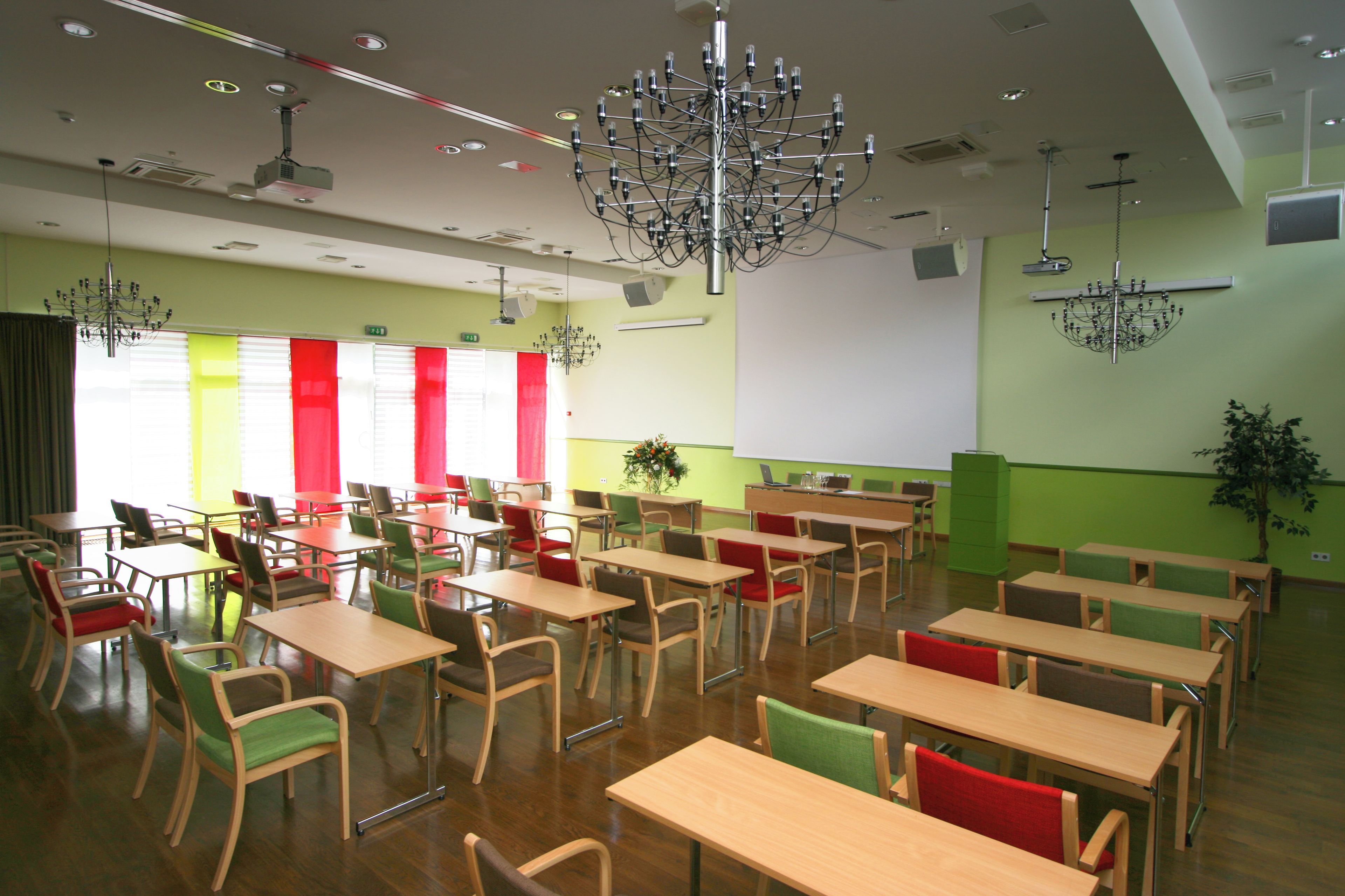 A classroom with multiple tables and chairs, a projector, and a screen.