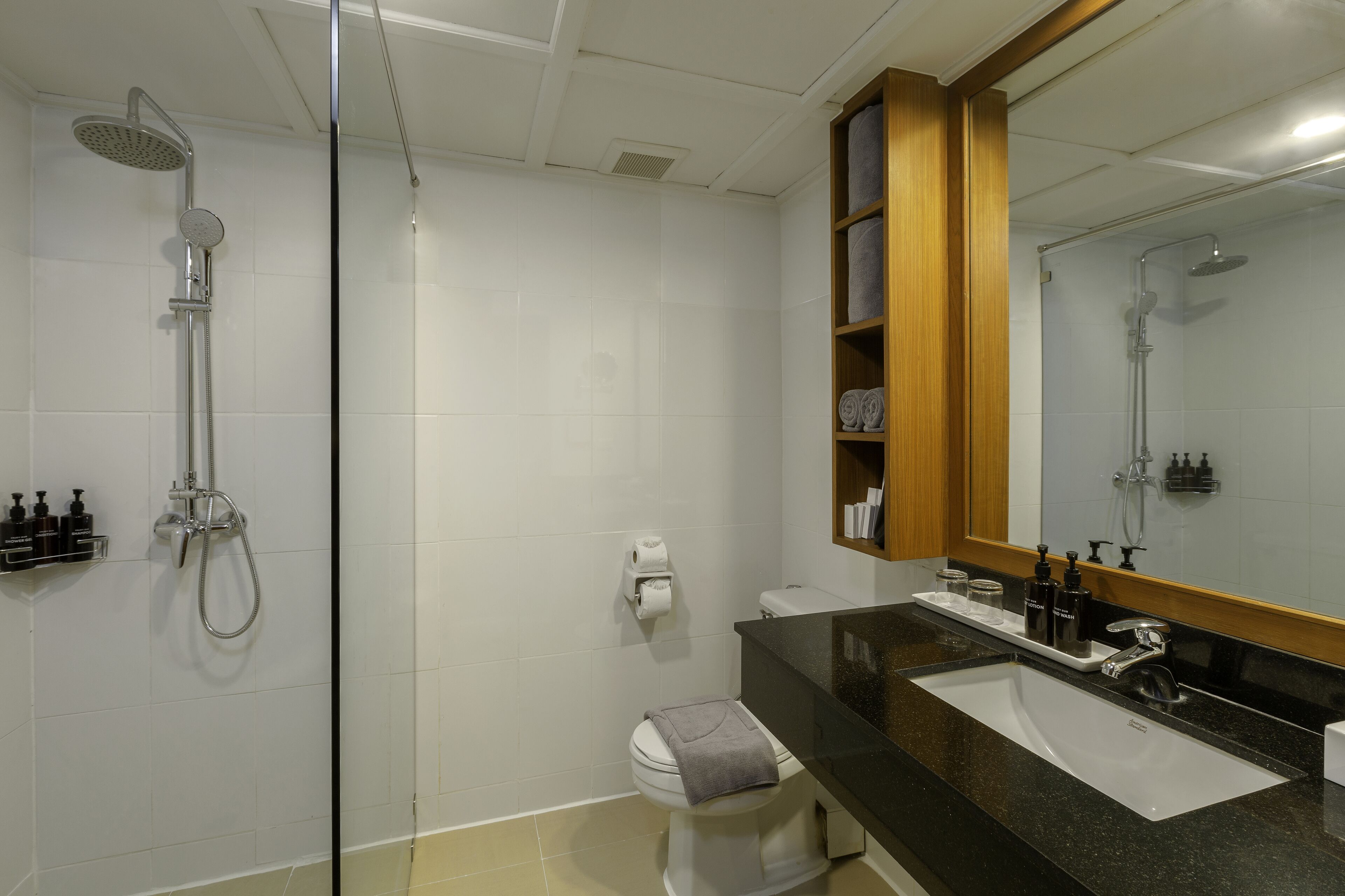 A modern bathroom with a glass-enclosed shower, a black countertop, and a large mirror.