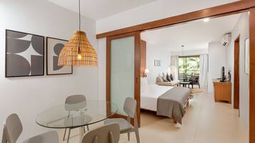 Une chambre d’hôtel moderne avec une table à manger en verre, un lit offrant une belle vue et une porte coulissante à cadre en bois.