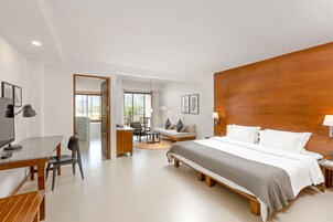 Una habitación de hotel moderna con una cama grande, un escritorio, un sofá y un comedor.