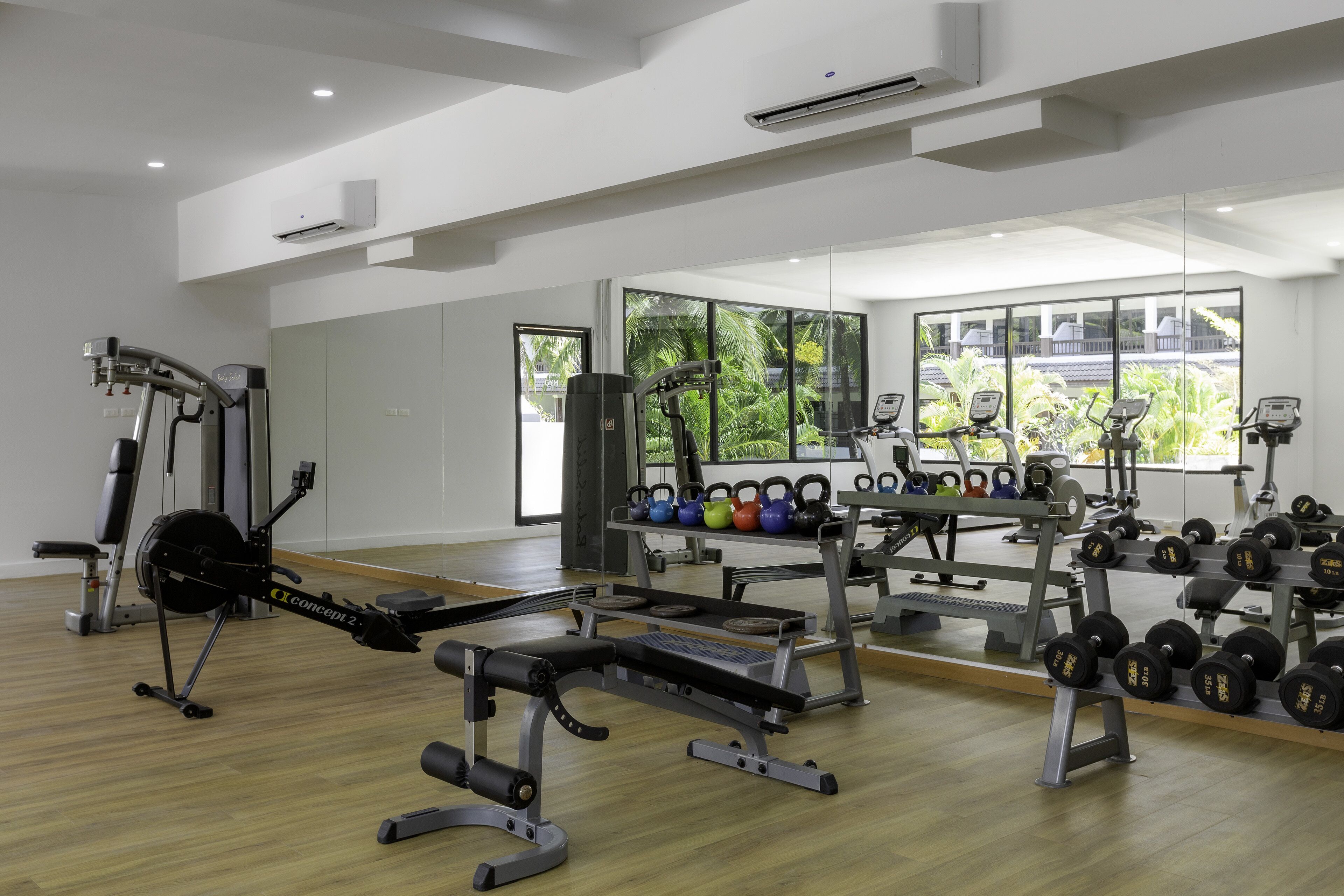 A gym with cardio equipment, weight benches, and kettlebells.