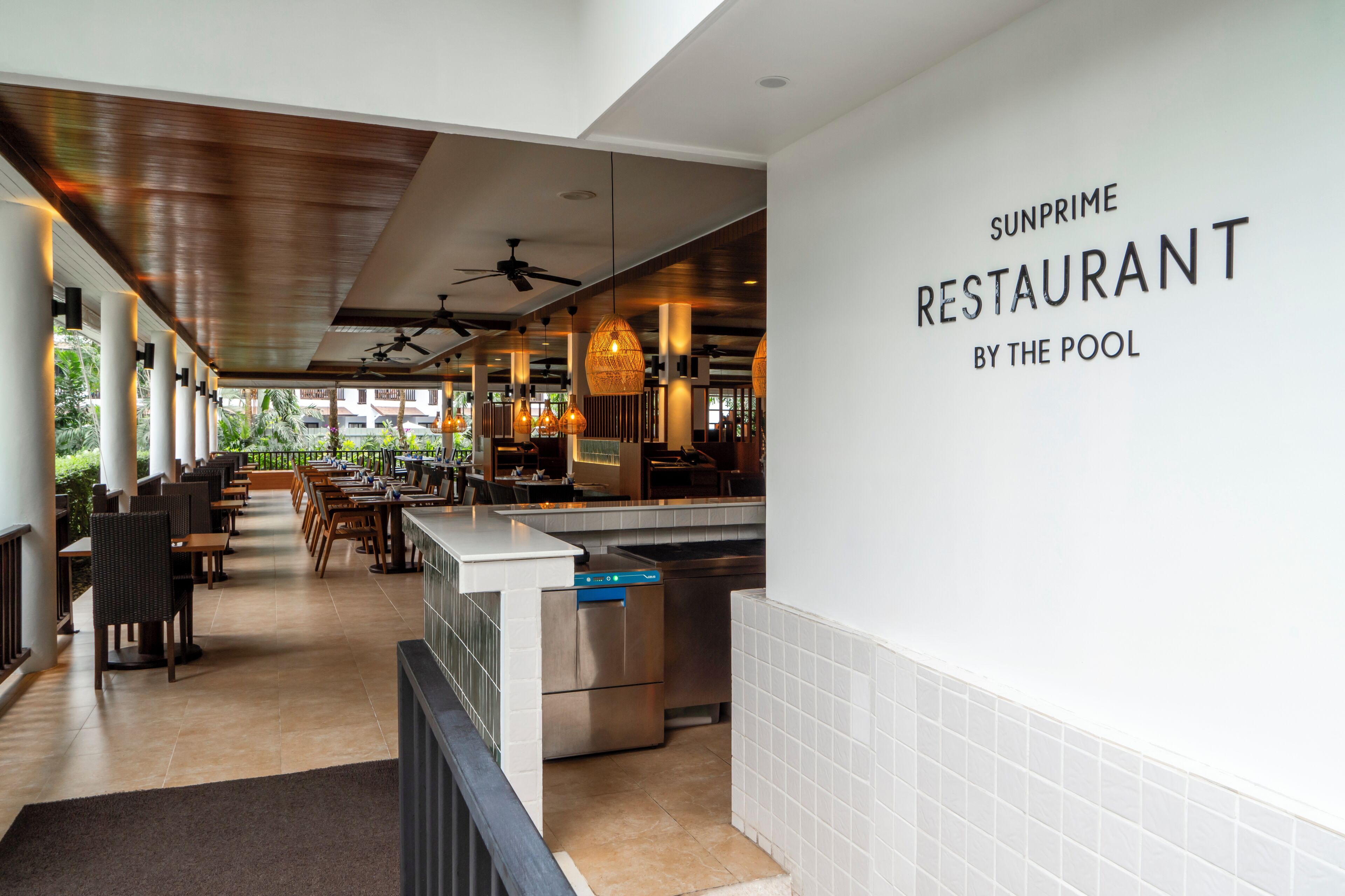 Un restaurante con vista a la piscina, con un interior moderno que incluye ventiladores de techo, luces colgantes y una zona de bar.