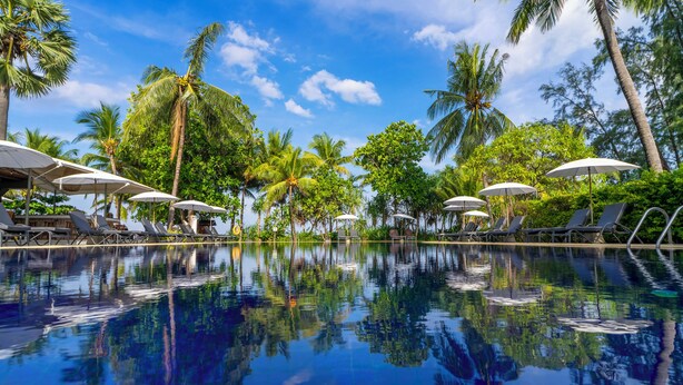 A pool with lounge chairs and umbrellas, surrounded by palm trees. - Sunprime Kamala Beach (Kamala)