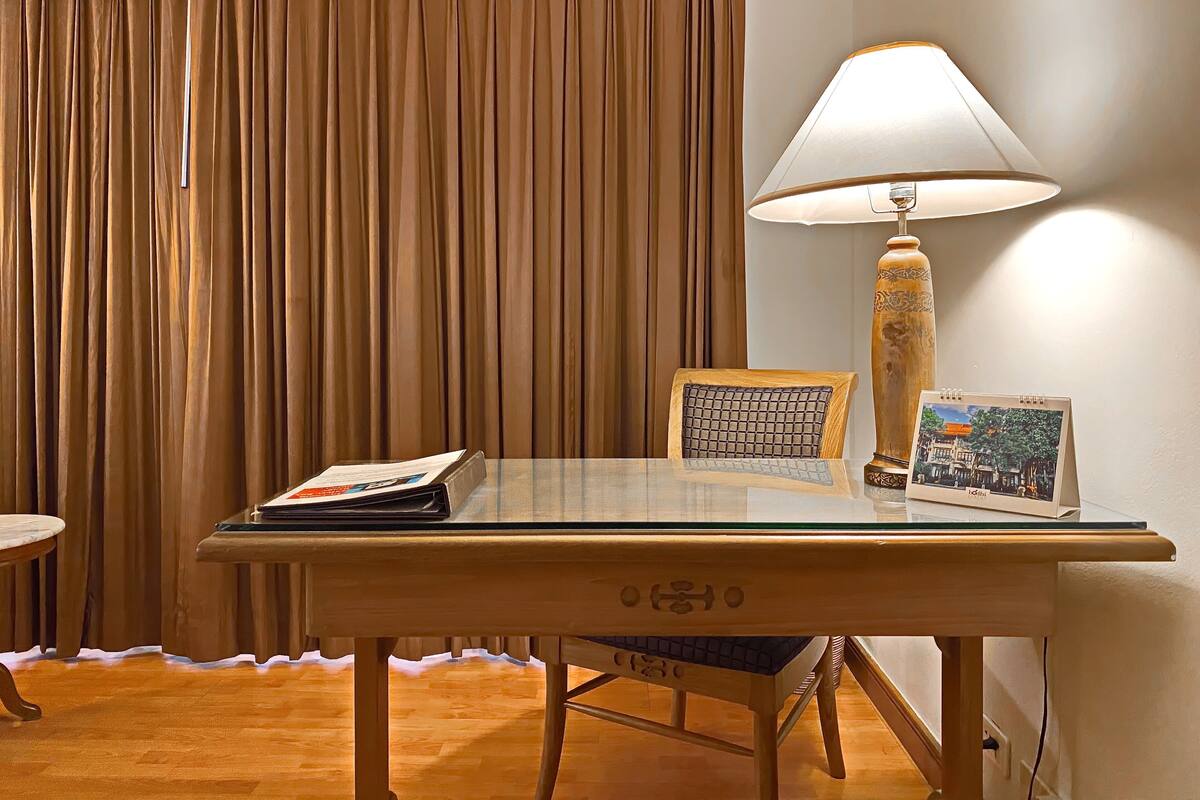 Ein Zimmer mit Glastisch, Lampe, Stuhl, Zeitschrift und gerahmtem Bild.