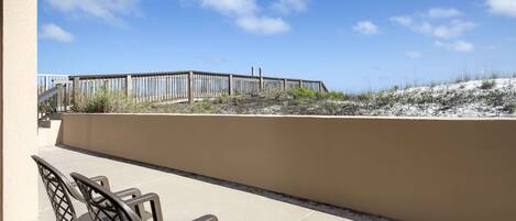 Un patio con mobiliario exterior y vistas a una zona de playa arenosa.