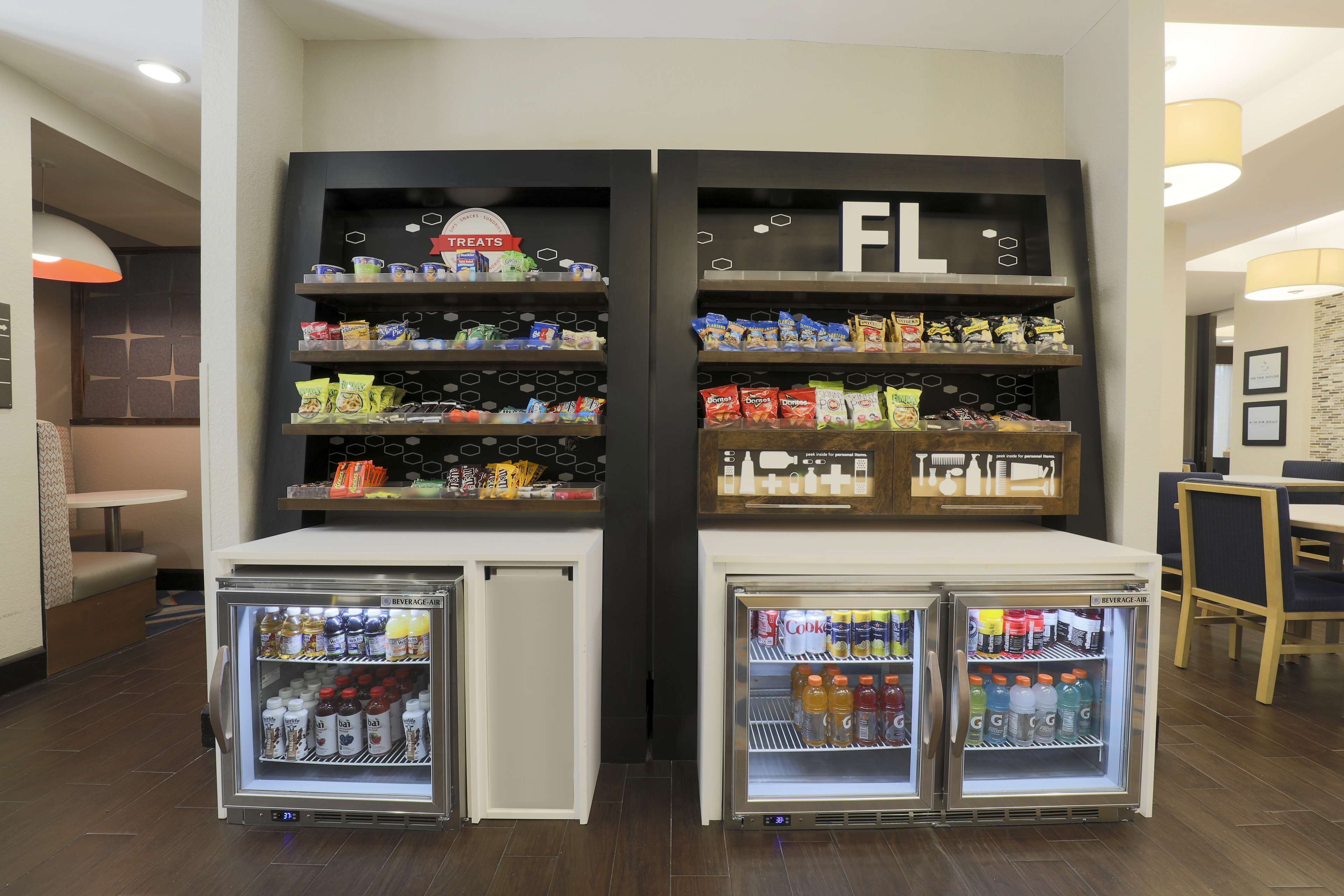 A beverage fridge with snacks and a sign indicating 'Treats' above it.