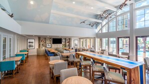 A spacious indoor area with multiple seating arrangements, including tables and chairs, and a long bar counter. - Hampton Inn and Suites Amelia Island Historic Harbor Front (Fernandina Beach)