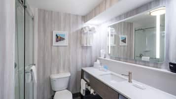 A modern bathroom with a toilet, sink, and glass shower enclosure.