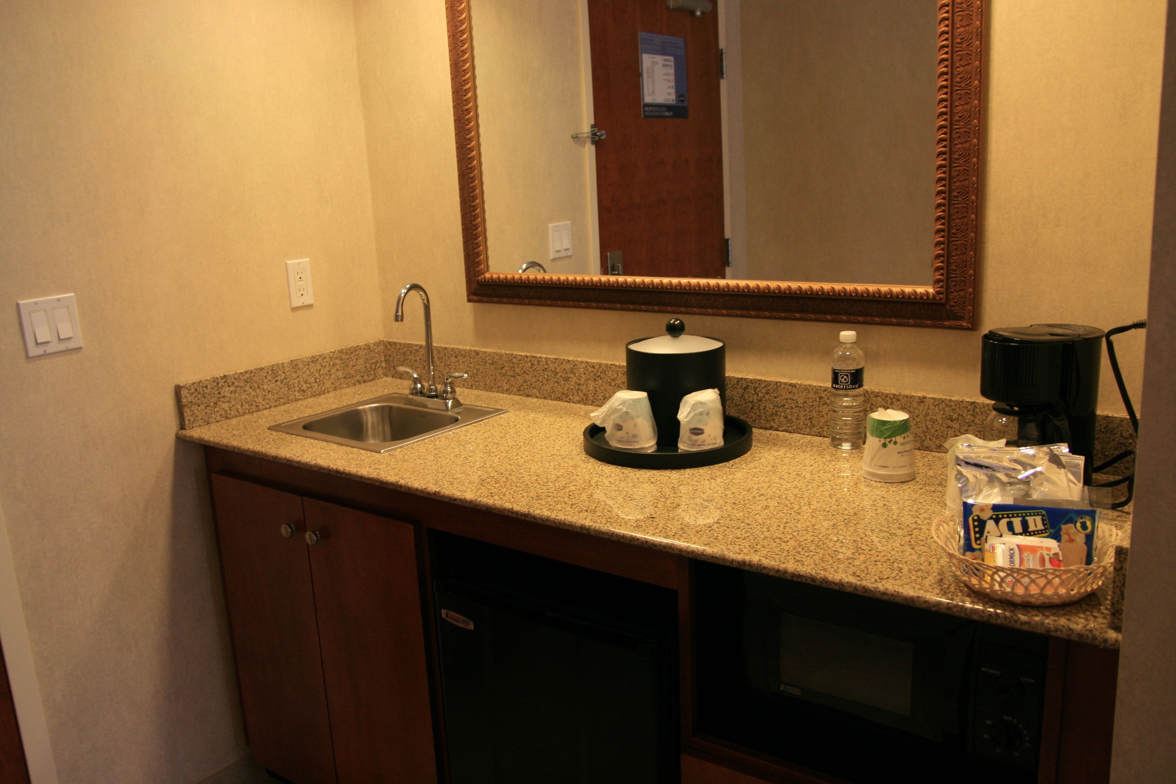 Une salle de bain d’hôtel équipée d’un lavabo, d’un miroir et d’une machine à café.