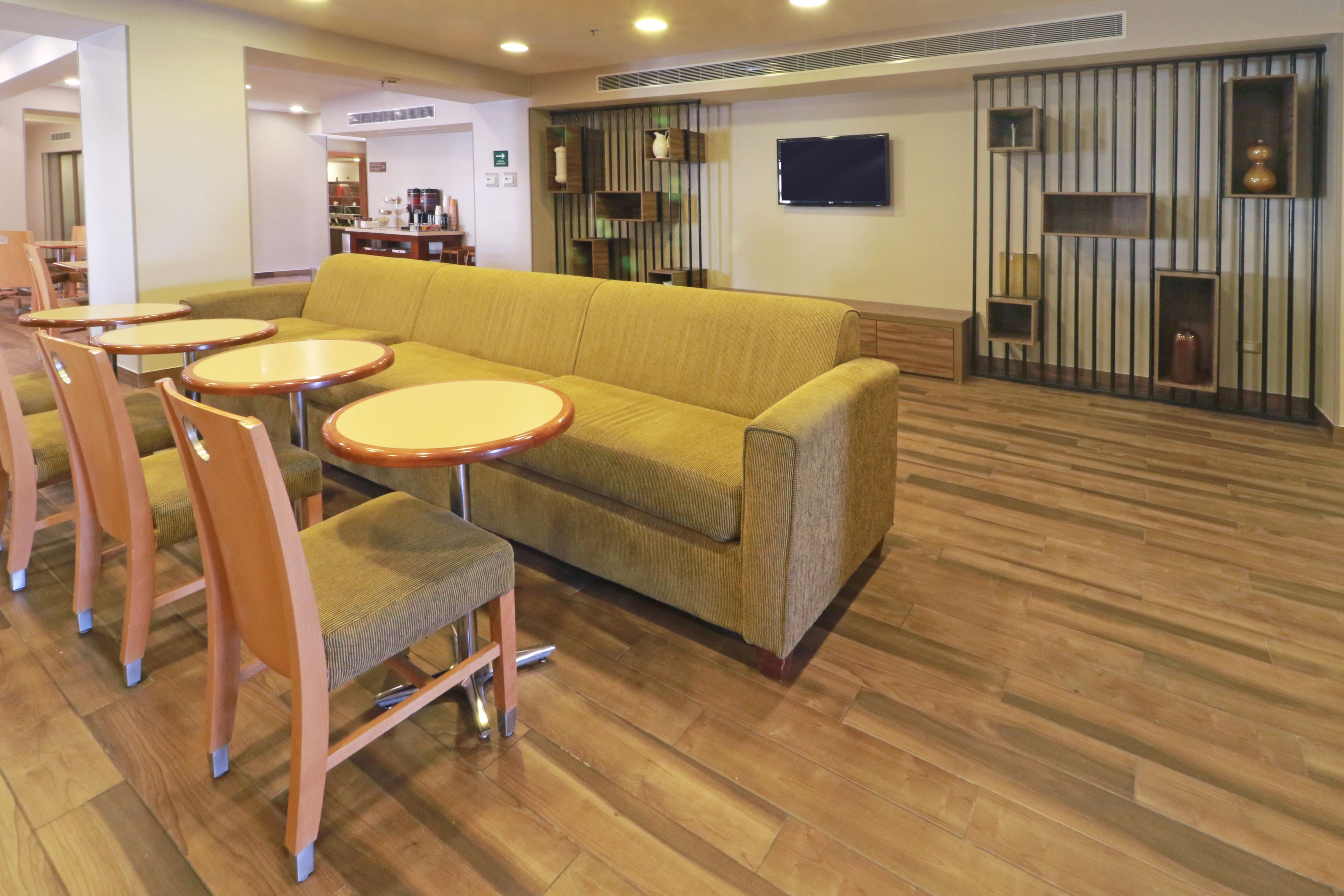 A hotel lobby with a sofa, round tables, and chairs.