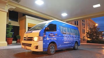 Una camioneta azul estacionada frente a un edificio con el texto "It's a good day" y "hampton.com" en su lateral.