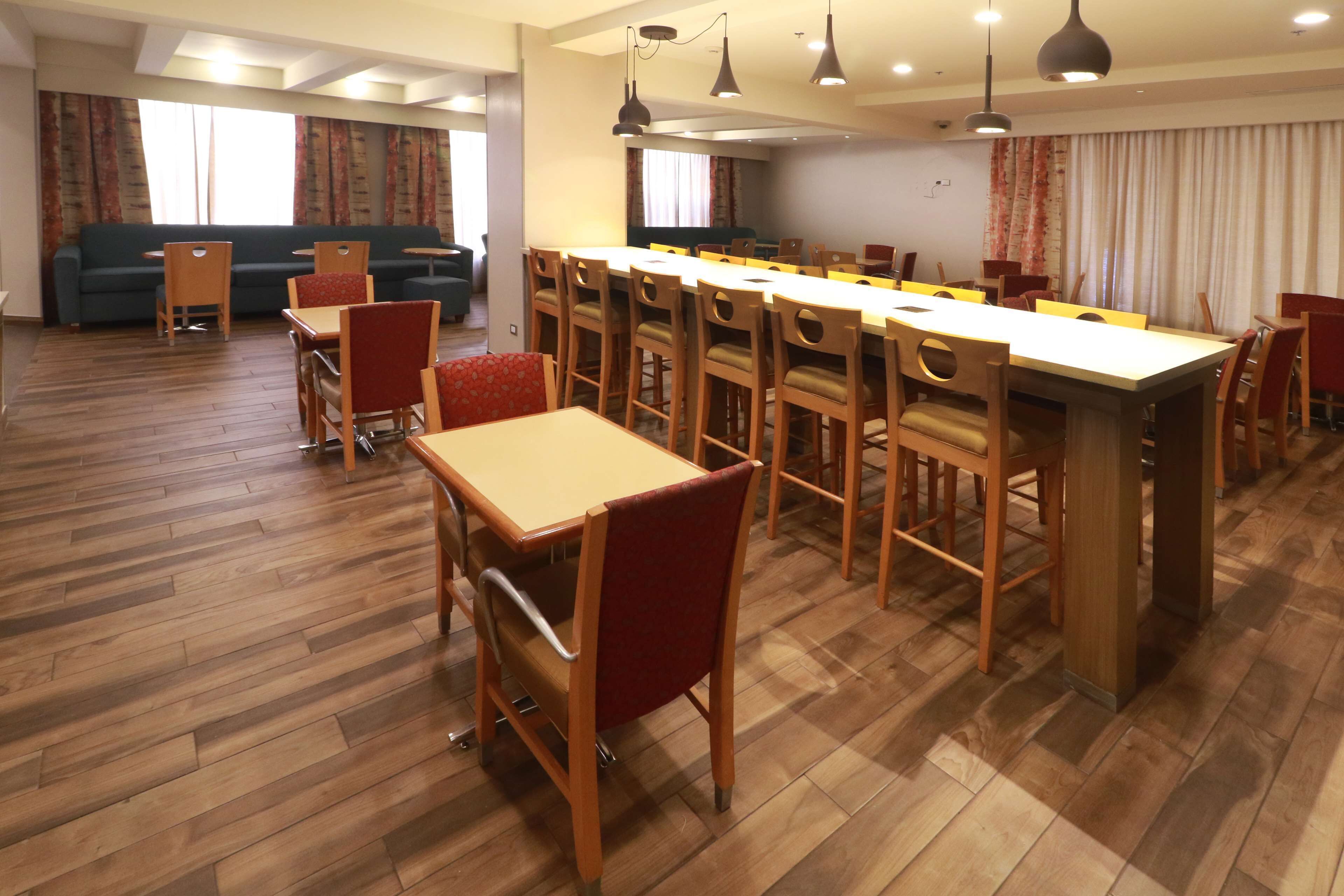 Un comedor espacioso con una mesa larga y varias sillas, un sofá al fondo y suelo de madera.