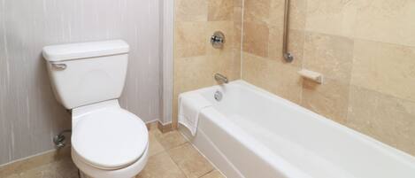 A bathroom with a toilet, a bathtub, and a shower area.
