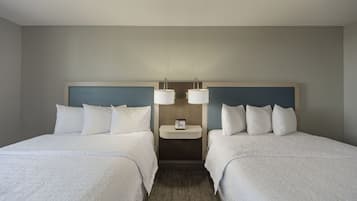 Una habitación de hotel con dos camas, una mesita de noche y una lámpara fijada en la pared.