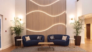Un hall moderno con dos sofás, una mesa de centro de madera y plantas en macetas.