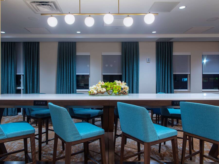 A conference room with a long table, blue chairs, and a vase of flowers.