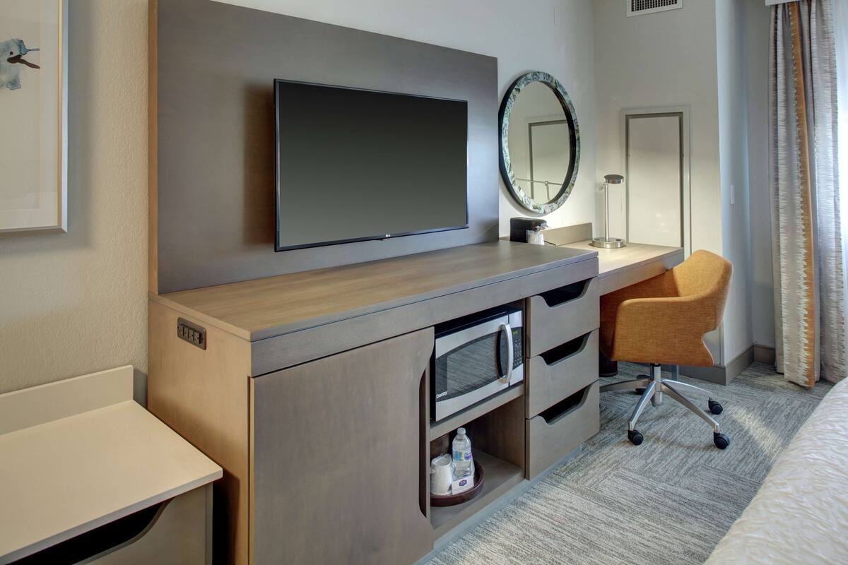 Une chambre d’hôtel équipée d’un téléviseur à écran plat, d’un four à micro-ondes, d’un lavabo et d’une chaise.