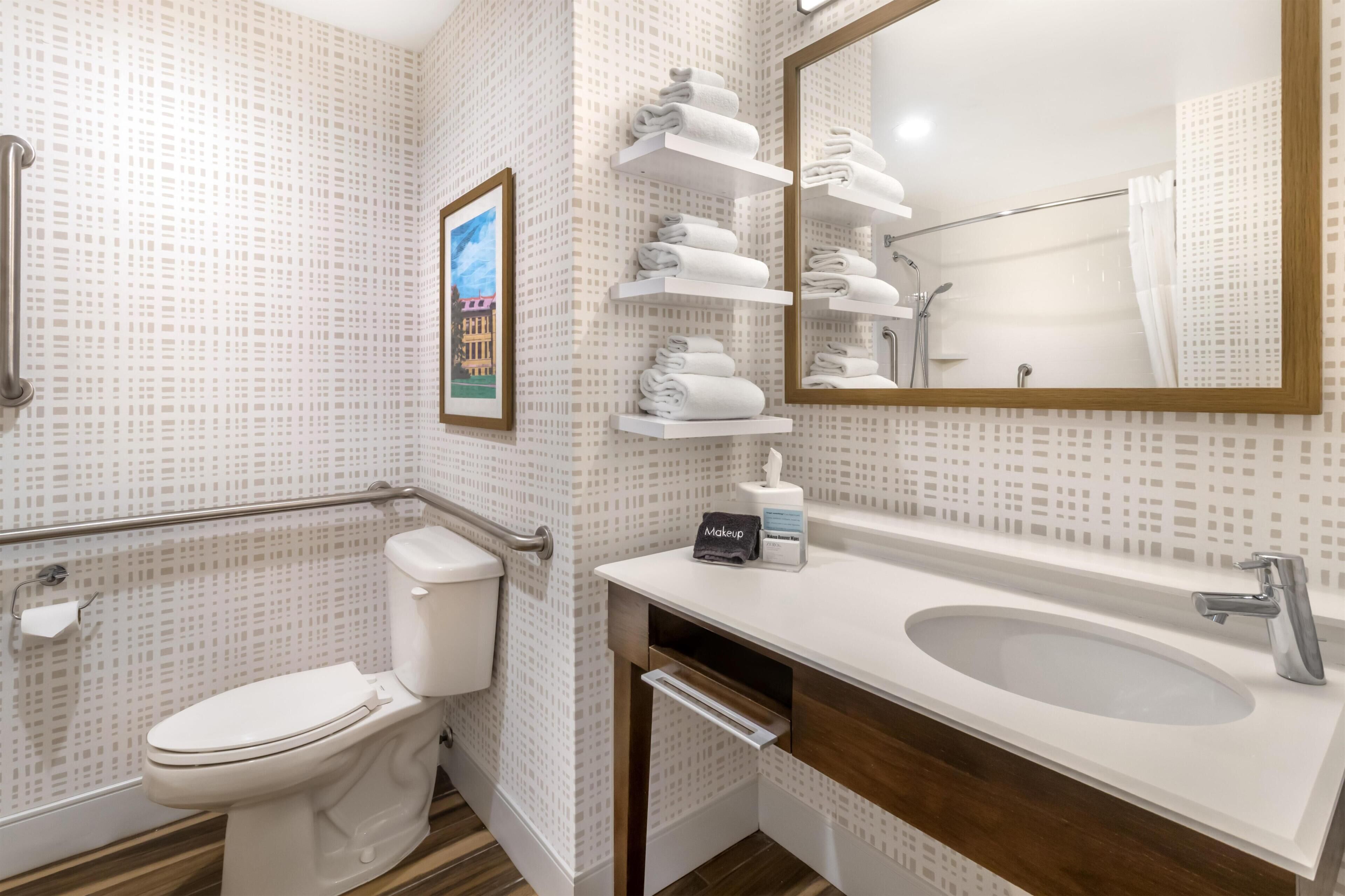 A bathroom with a toilet, a sink, a mirror, and a towel rack.