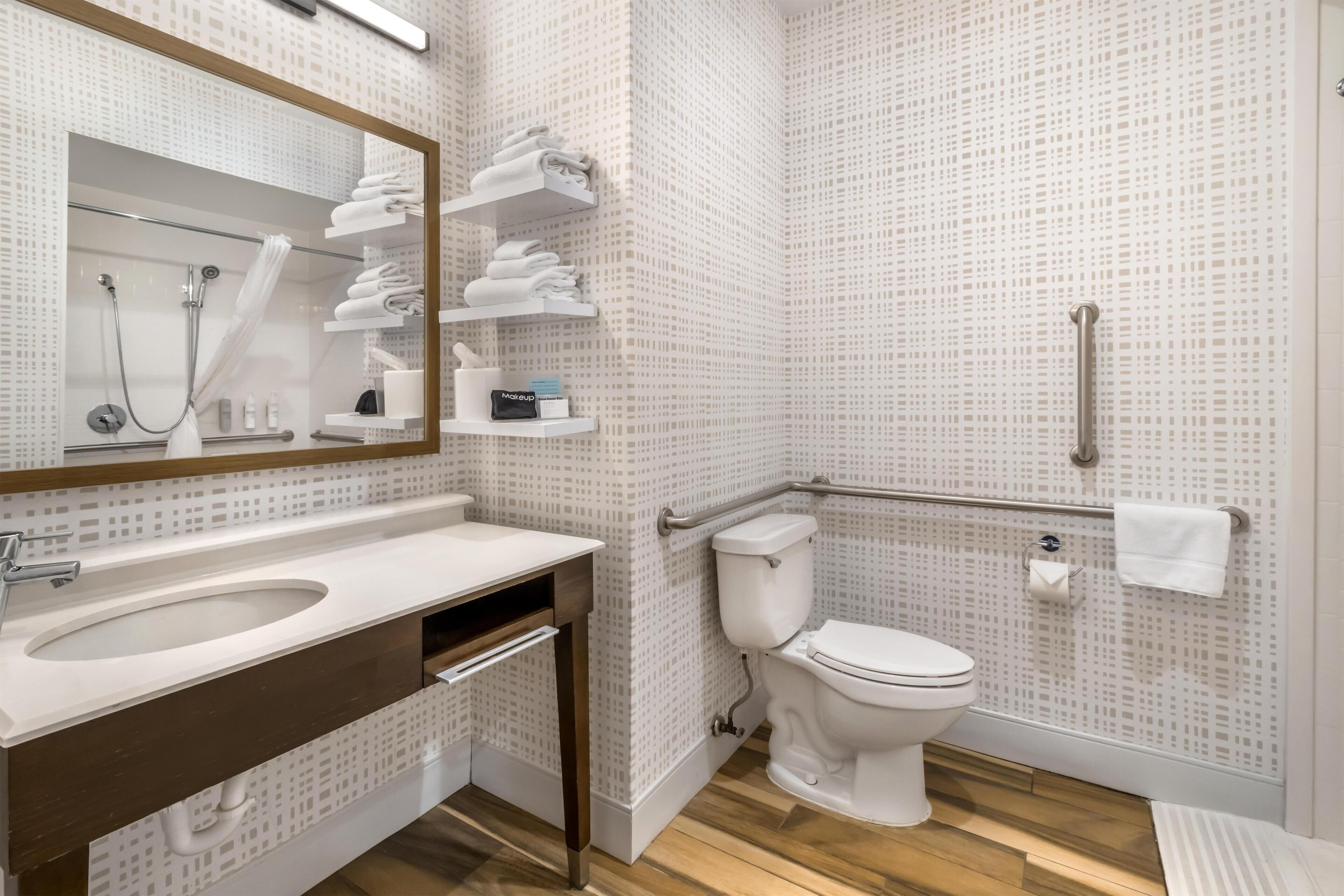 A modern bathroom with a sink, mirror, toilet, and shower.