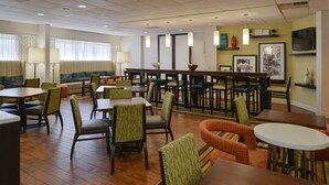 Ein Speisesaal eines Hotels mit mehreren Tischen, Stühlen, einer Bar und einer Sitzecke.