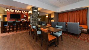 A hotel lobby with a dining area, a bar, and a seating area with curtains. - Hampton Inn Chicago-Carol Stream (Carol Stream)