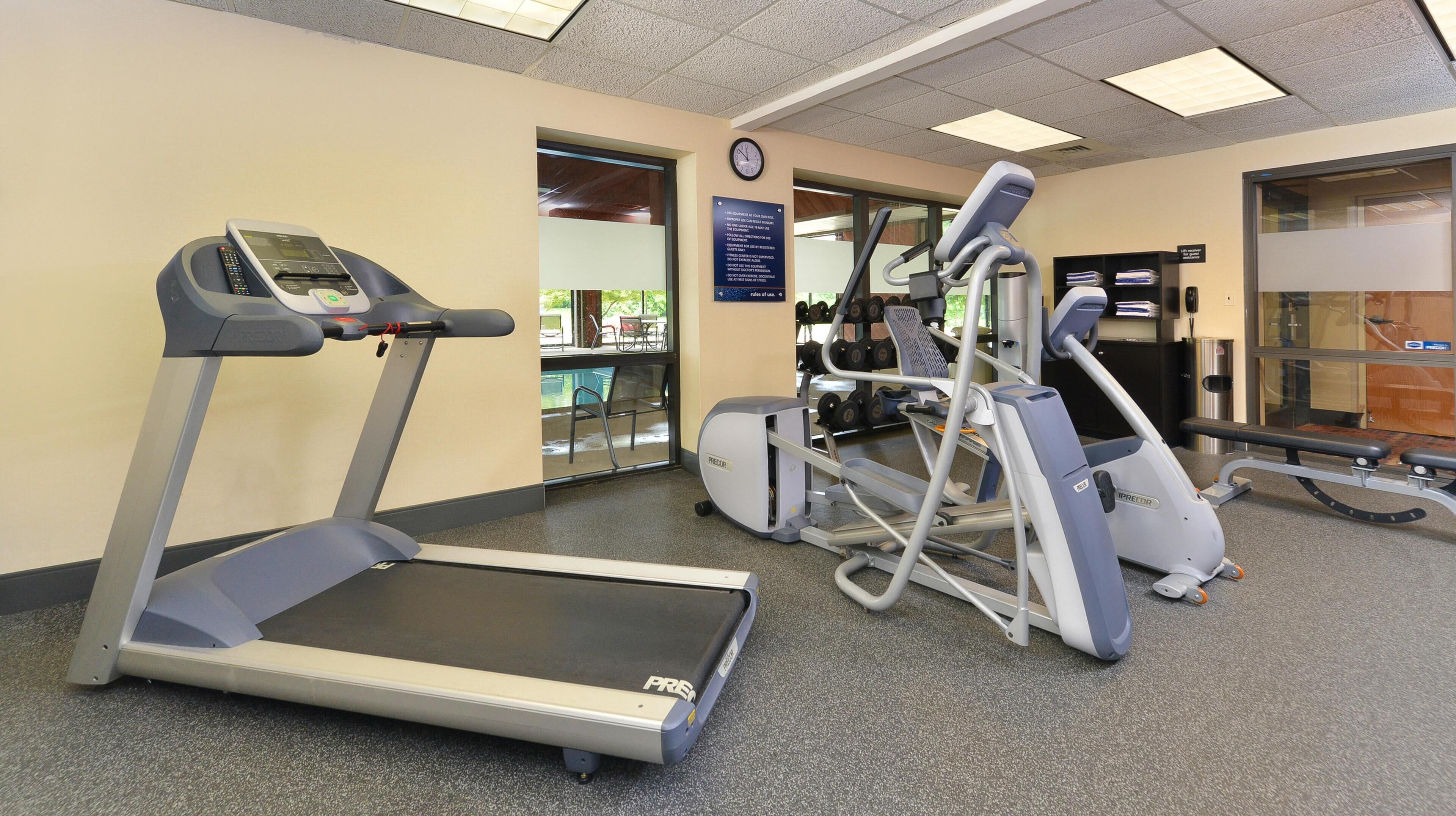 Une salle de sport équipée de tapis de course, de vélos elliptiques et d’appareils de musculation.